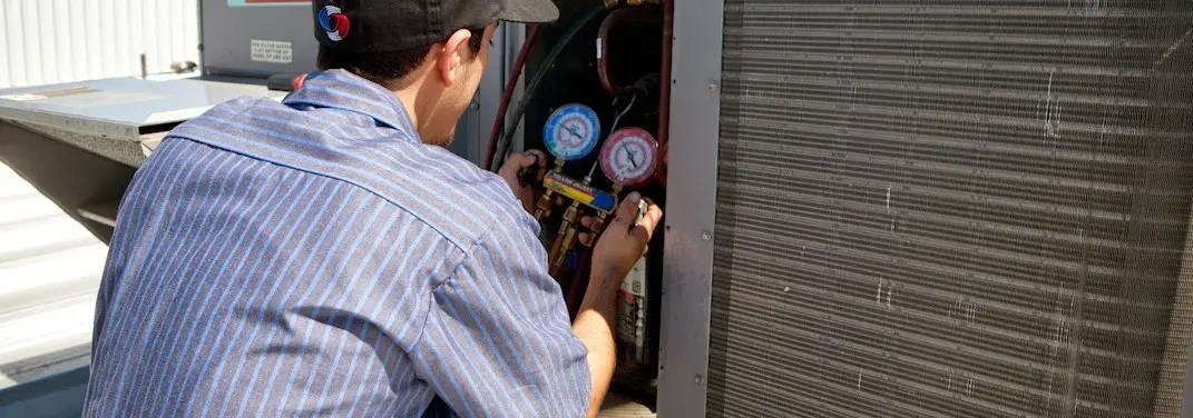 HVAC technician servicing a condenser unit in Walker Mill